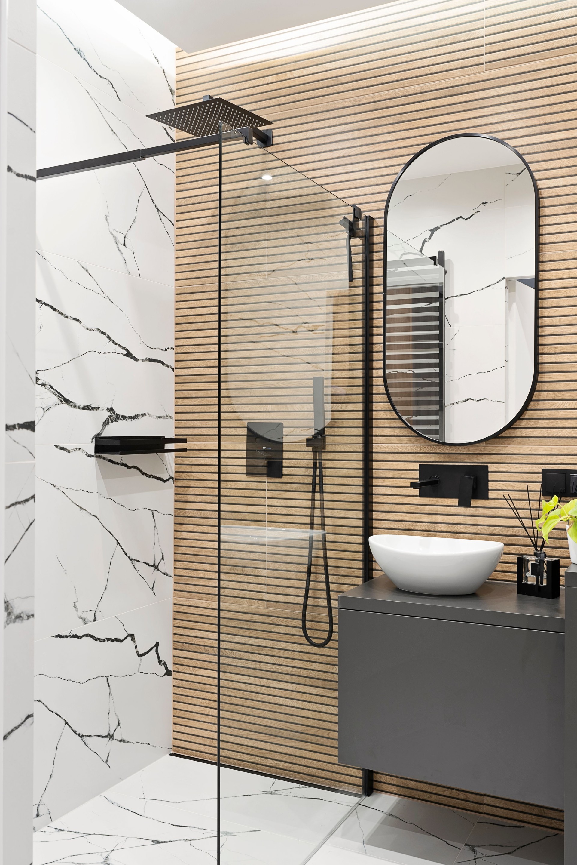 Interior decor. Ceramic bathroom sink with black water tap and tile with marbled effect on the wall and modern shower with glass. Real estate. Vertical.